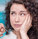 Woman with curly hair holding jaw